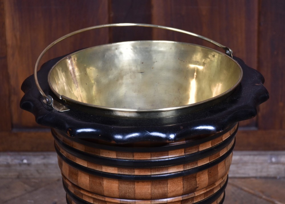 A 19th-century Dutch wooden teestoof featuring alternating light and dark wood parquetry, ebonised trim, turned pedestal base on ball feet, and a removable brass liner with a swing handle. View II