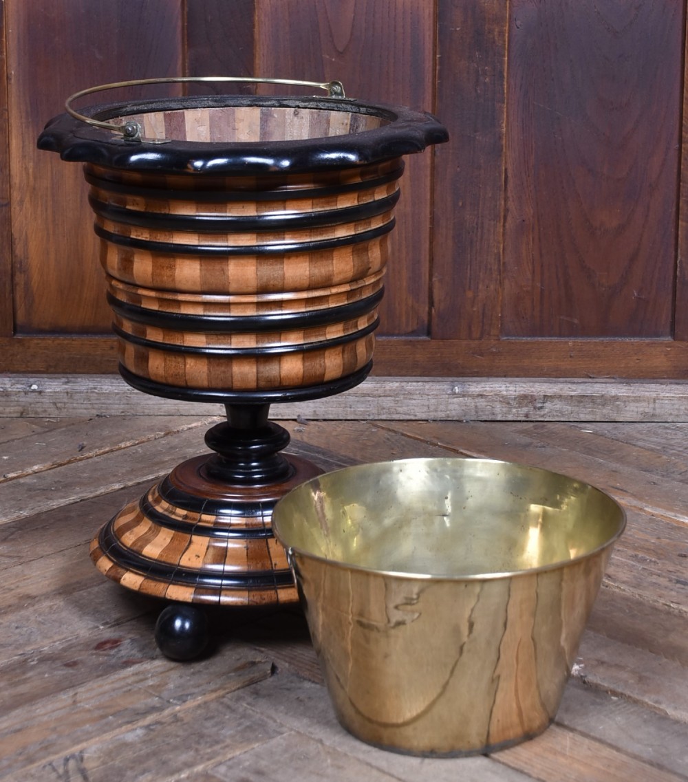 A 19th-century Dutch wooden teestoof featuring alternating light and dark wood parquetry, ebonised trim, turned pedestal base on ball feet, and a removable brass liner with a swing handle. View V