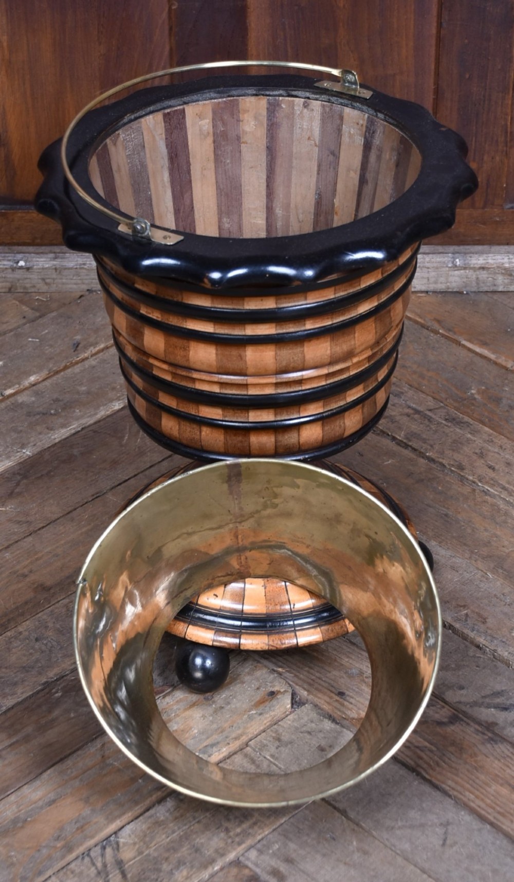 A 19th-century Dutch wooden teestoof featuring alternating light and dark wood parquetry, ebonised trim, turned pedestal base on ball feet, and a removable brass liner with a swing handle. View VII