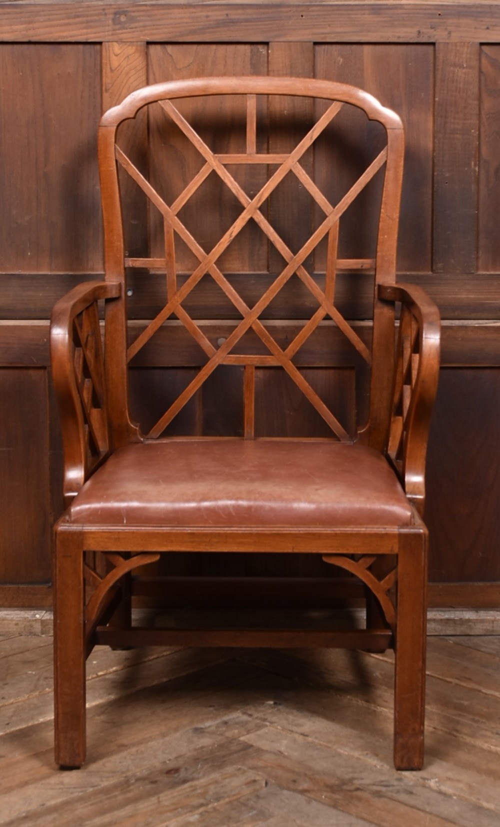 A 19th-century mahogany cockpen armchair featuring geometric lattice fretwork on the backrest and arms, complete with a brown leather drop-in seat. View II
