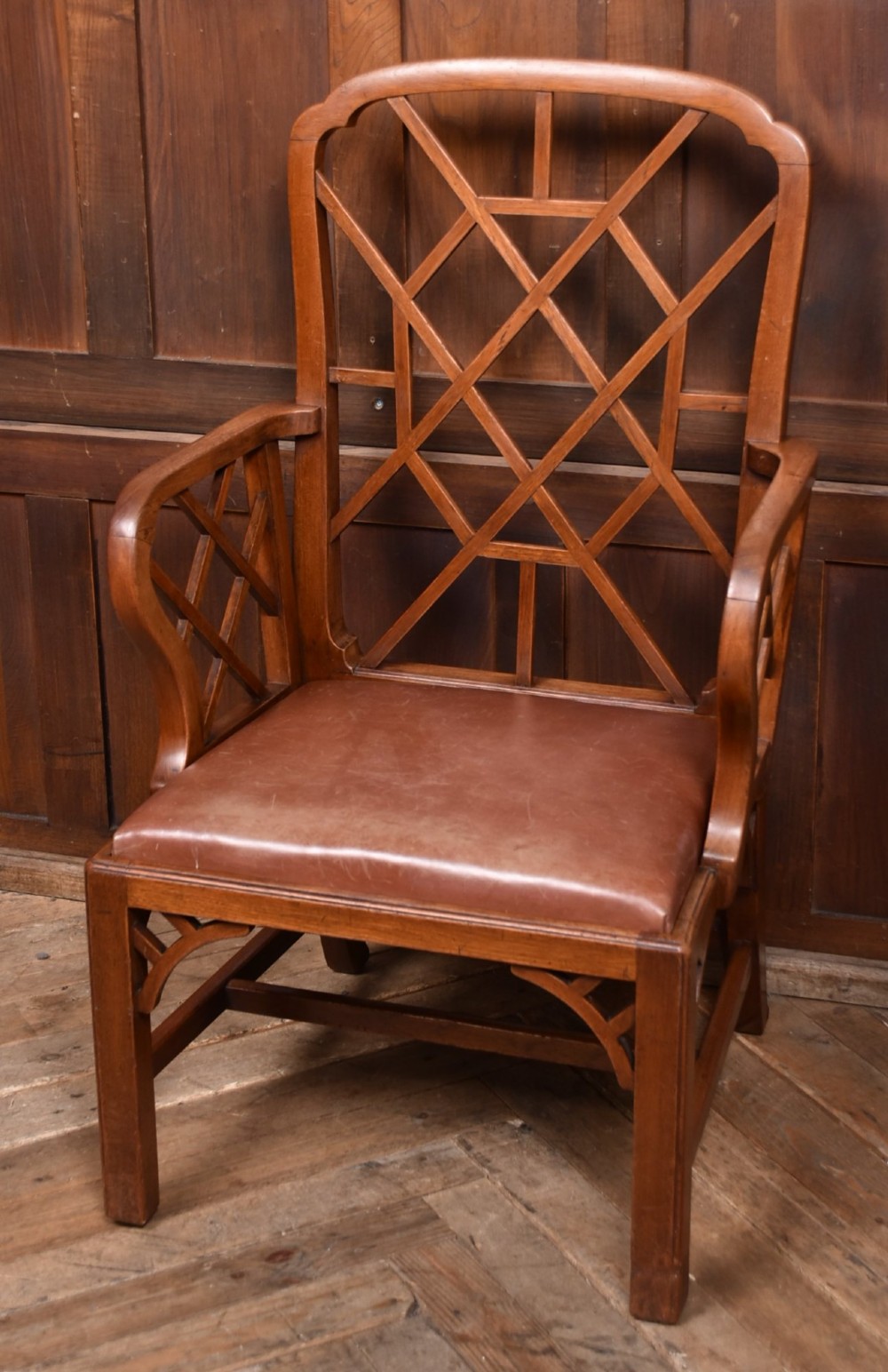 A 19th-century mahogany cockpen armchair featuring geometric lattice fretwork on the backrest and arms, complete with a brown leather drop-in seat. View III