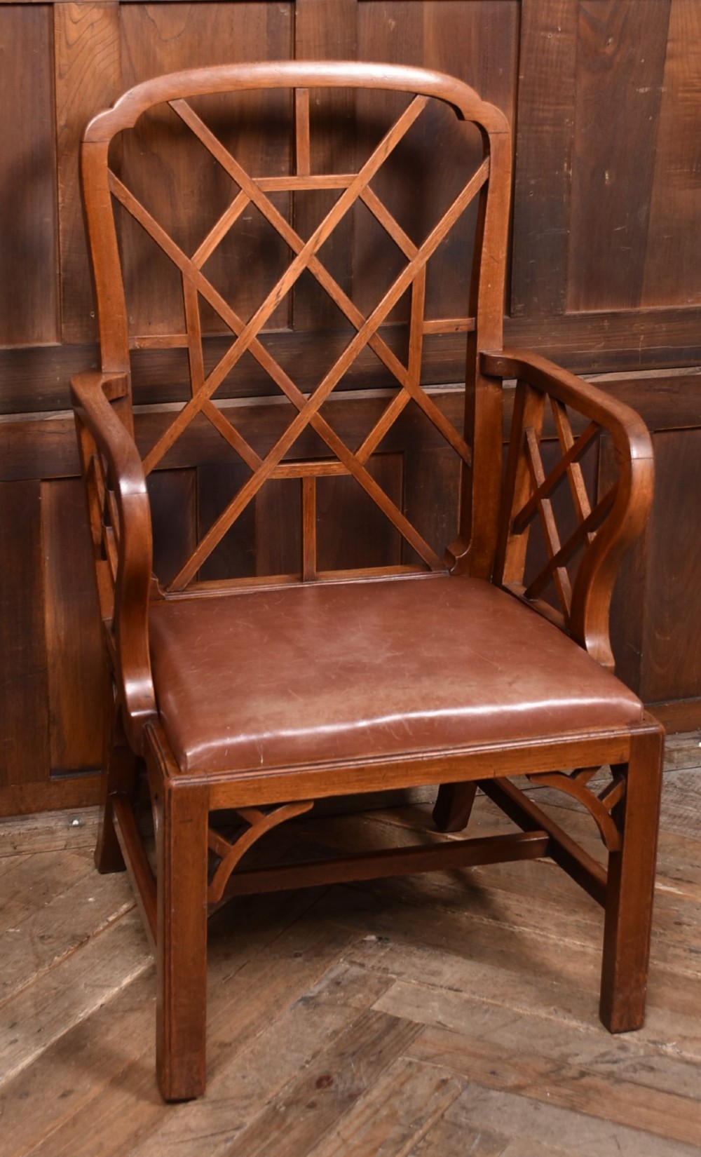 A 19th-century mahogany cockpen armchair featuring geometric lattice fretwork on the backrest and arms, complete with a brown leather drop-in seat. View IV
