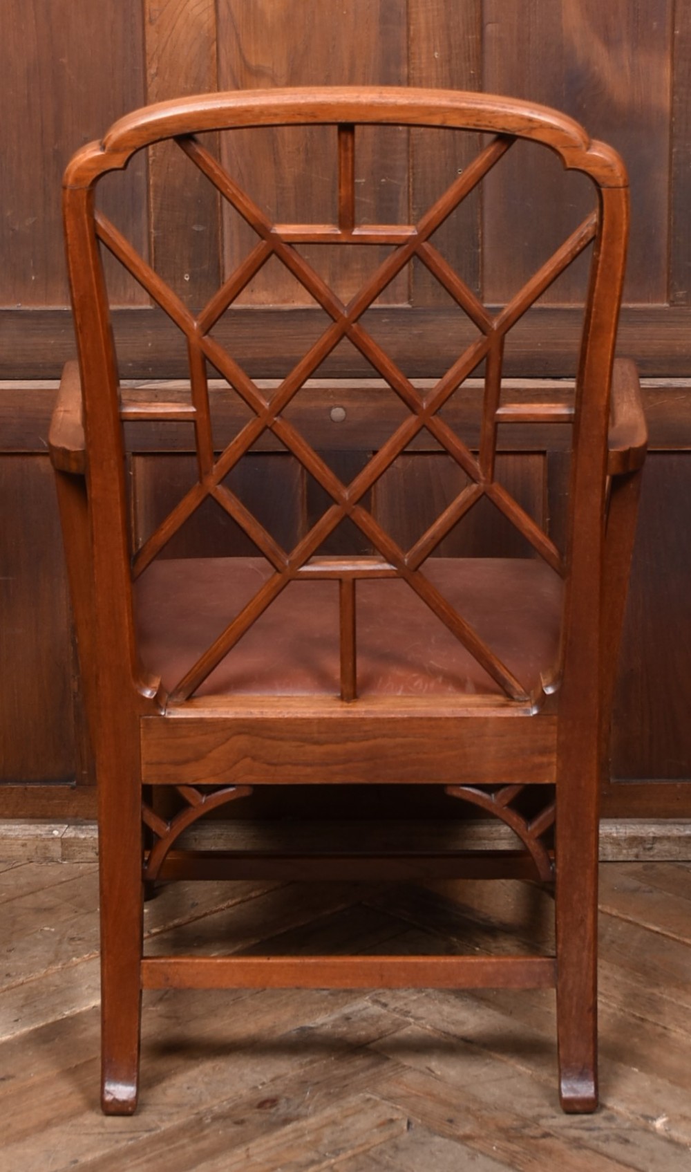 A 19th-century mahogany cockpen armchair featuring geometric lattice fretwork on the backrest and arms, complete with a brown leather drop-in seat. View VI