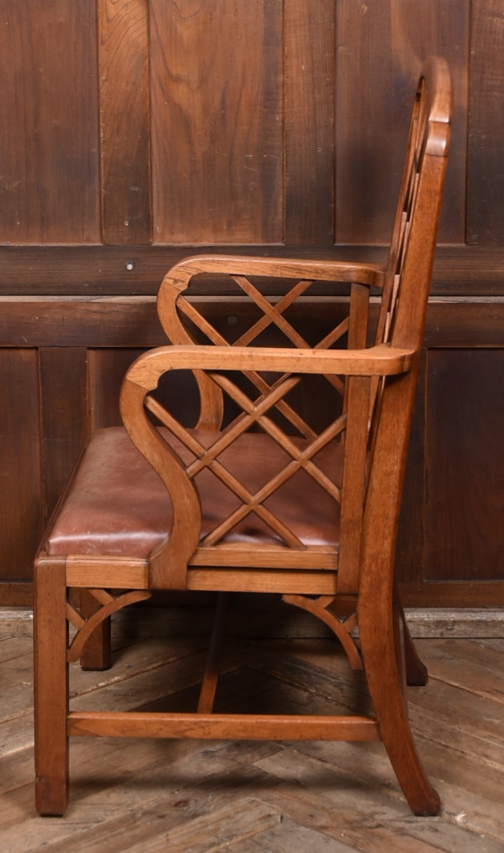 A 19th-century mahogany cockpen armchair featuring geometric lattice fretwork on the backrest and arms, complete with a brown leather drop-in seat. View VII