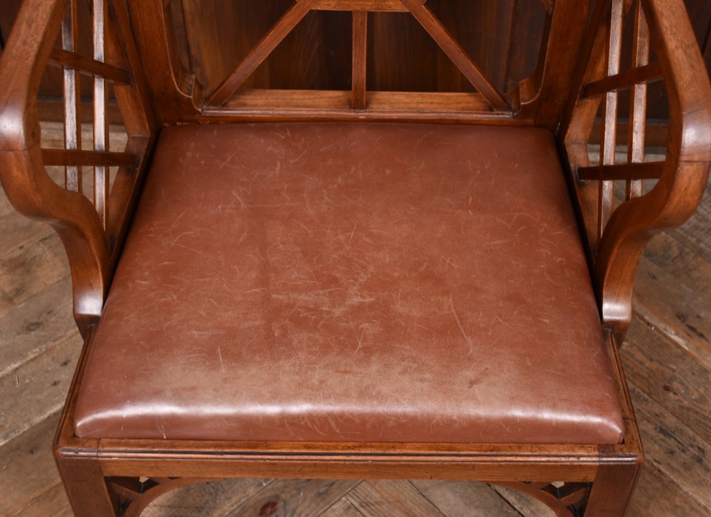 A 19th-century mahogany cockpen armchair featuring geometric lattice fretwork on the backrest and arms, complete with a brown leather drop-in seat. View VIII