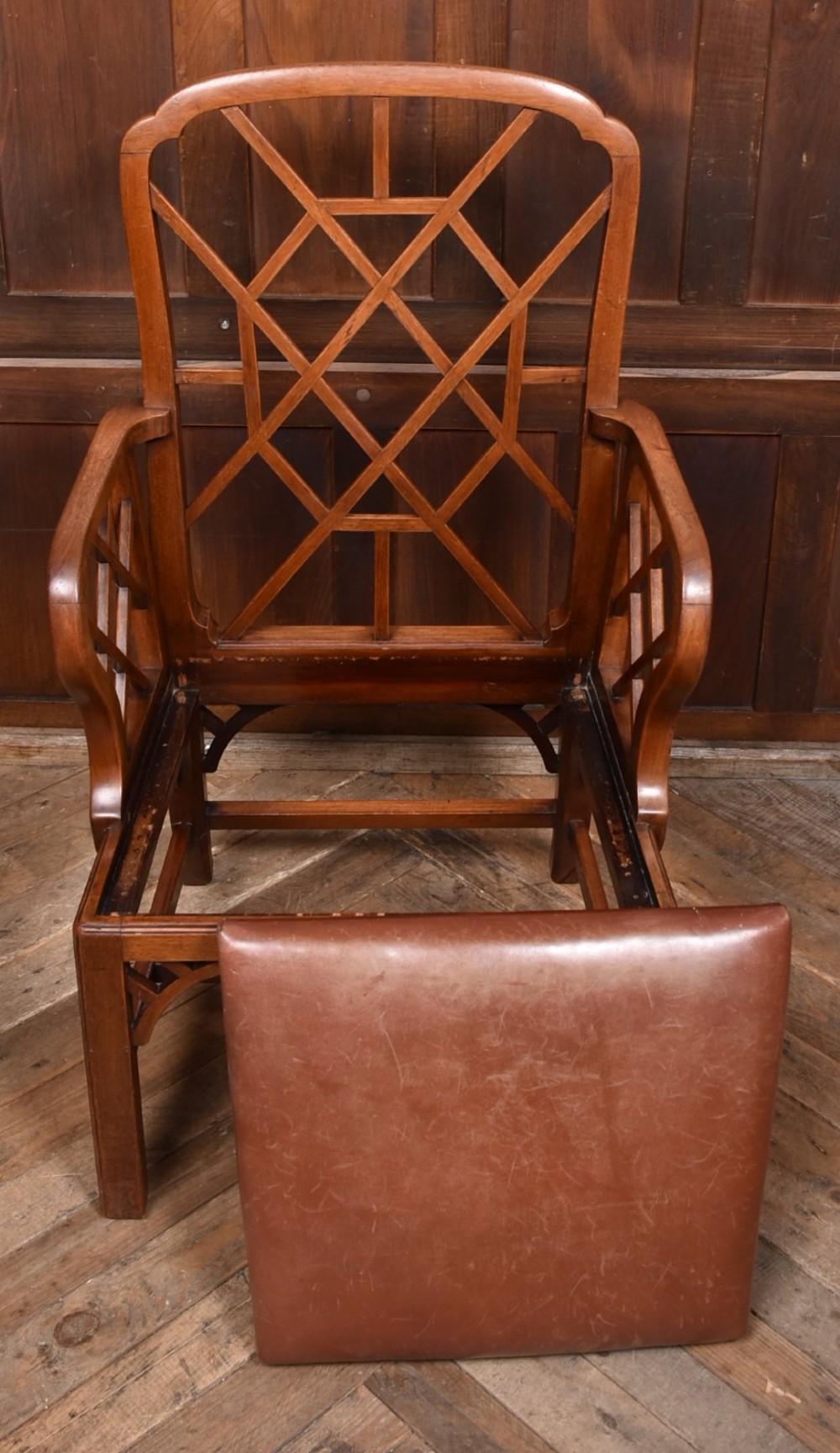 A 19th-century mahogany cockpen armchair featuring geometric lattice fretwork on the backrest and arms, complete with a brown leather drop-in seat. View IX