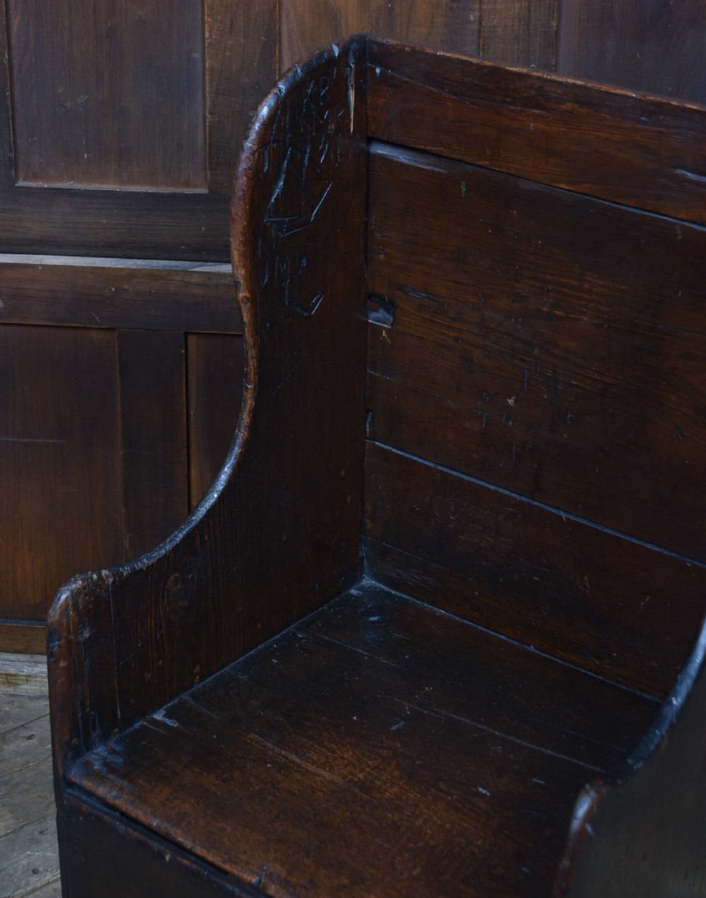 A 19th-century childs lambing chair crafted from dark oak, featuring high solid wings, a panelled backrest, an enclosed box seat, and short square legs. View VI