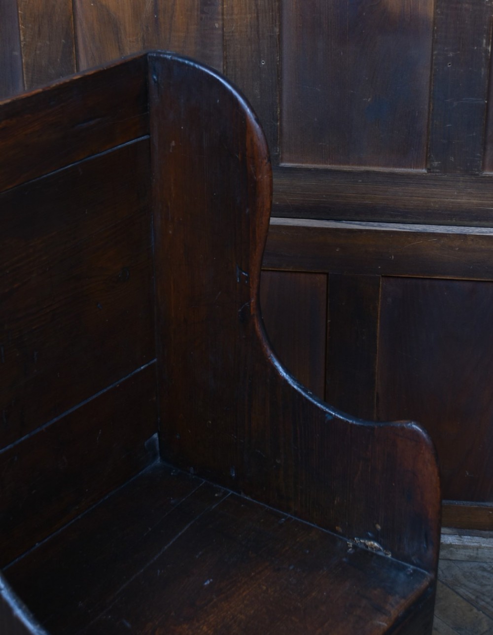 A 19th-century childs lambing chair crafted from dark oak, featuring high solid wings, a panelled backrest, an enclosed box seat, and short square legs. View VII