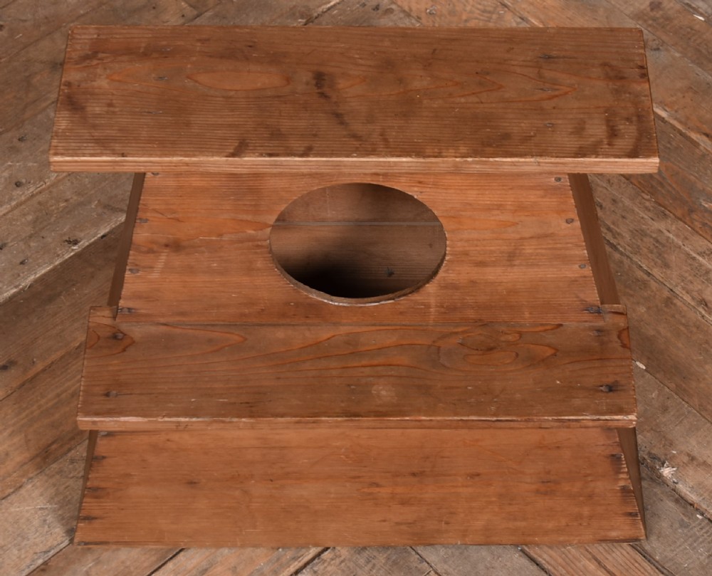 A warm brown wooden Japanese vendor stool featuring a stepped rectangular base, a circular front cutout opening, and a flat upper shelf. View VI