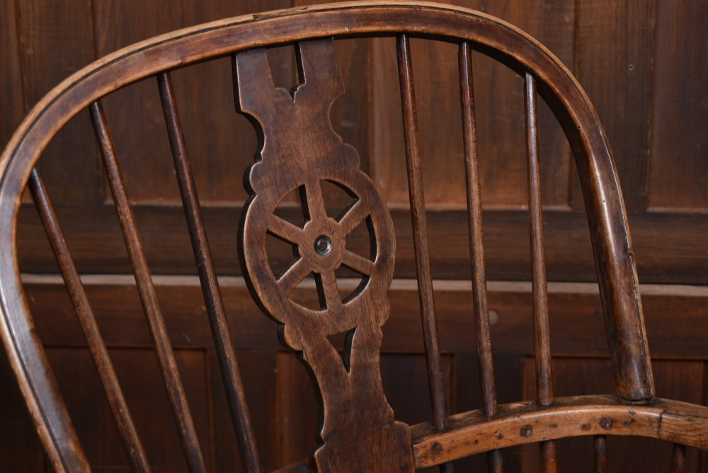 A 19th-century dark wood Windsor armchair featuring a pierced wheel back splat, spindle backrest, curved armrests, shaped seat, and turned legs. View II