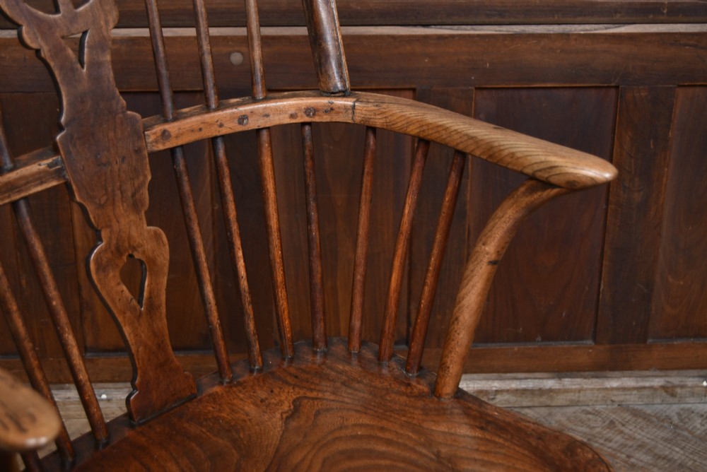 A 19th-century dark wood Windsor armchair featuring a pierced wheel back splat, spindle backrest, curved armrests, shaped seat, and turned legs. View III