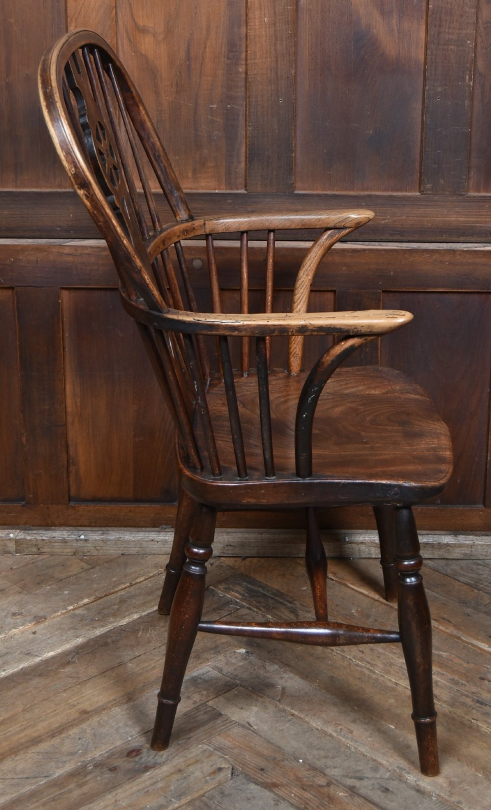 A 19th-century dark wood Windsor armchair featuring a pierced wheel back splat, spindle backrest, curved armrests, shaped seat, and turned legs. View VII