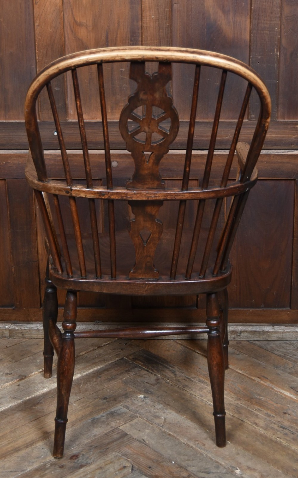 A 19th-century dark wood Windsor armchair featuring a pierced wheel back splat, spindle backrest, curved armrests, shaped seat, and turned legs. View VIII