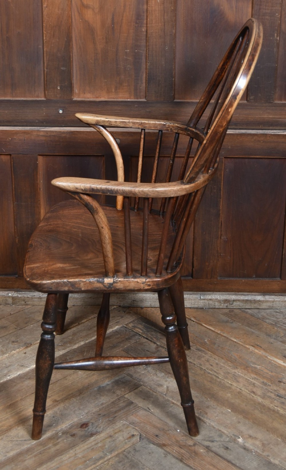 A 19th-century dark wood Windsor armchair featuring a pierced wheel back splat, spindle backrest, curved armrests, shaped seat, and turned legs. View IX
