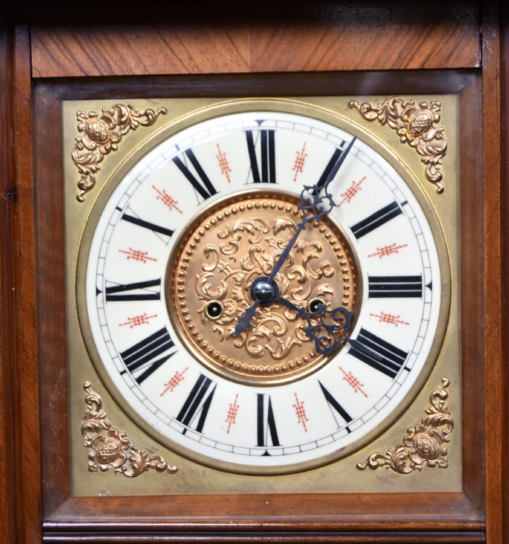 A late 19th-century Vienna-style wall clock featuring a dark walnut carved wood case, turned side columns, decorative pediment, brass weights, and a brass pendulum. View II