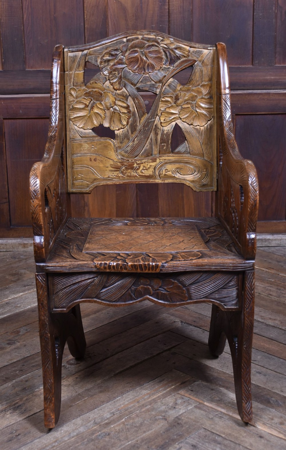 An antique carved walnut armchair featuring intricate floral relief carvings on the backrest, armrests, and legs. View II
