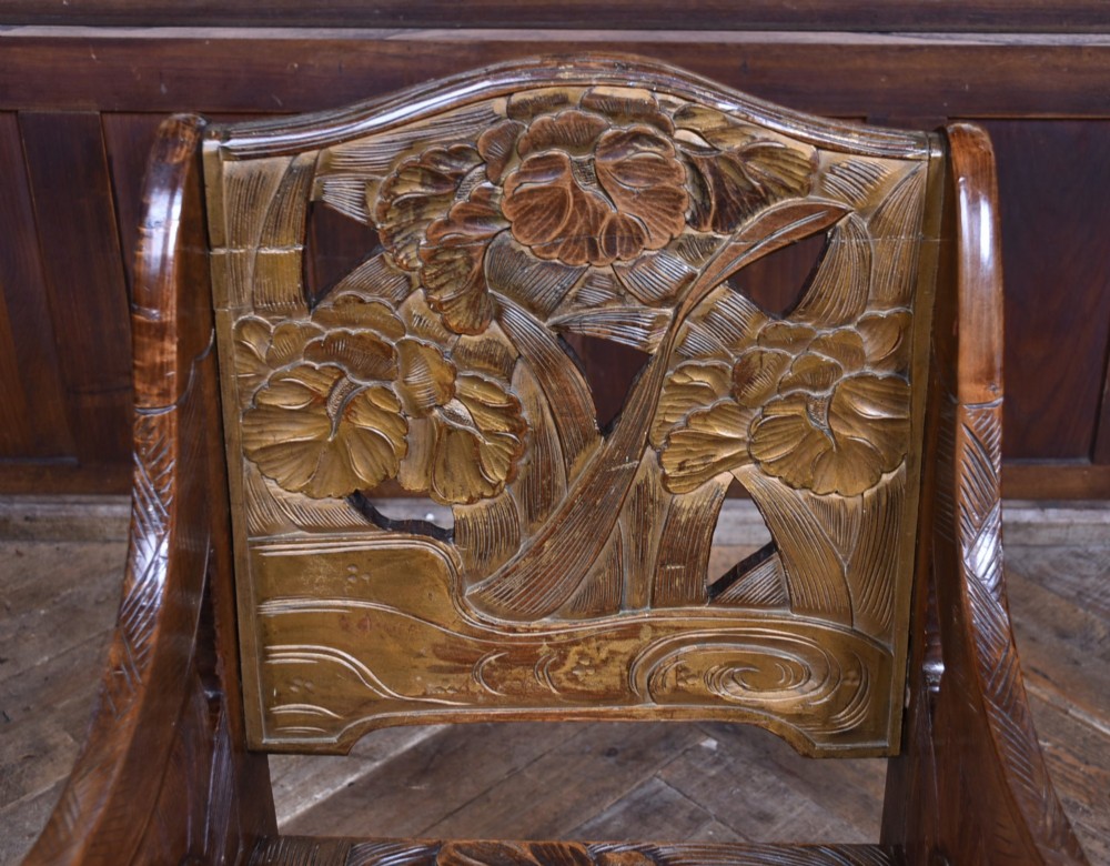 An antique carved walnut armchair featuring intricate floral relief carvings on the backrest, armrests, and legs. View III
