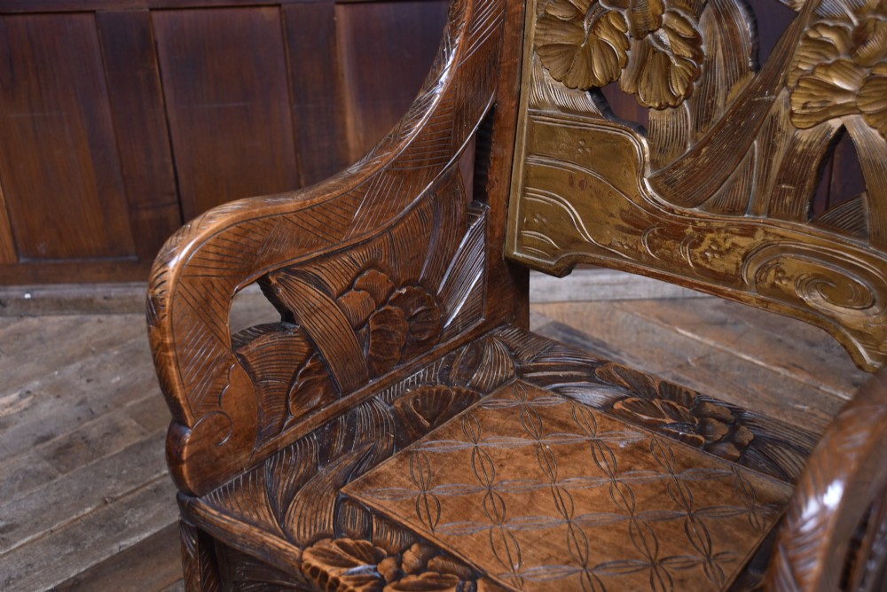 An antique carved walnut armchair featuring intricate floral relief carvings on the backrest, armrests, and legs. View V
