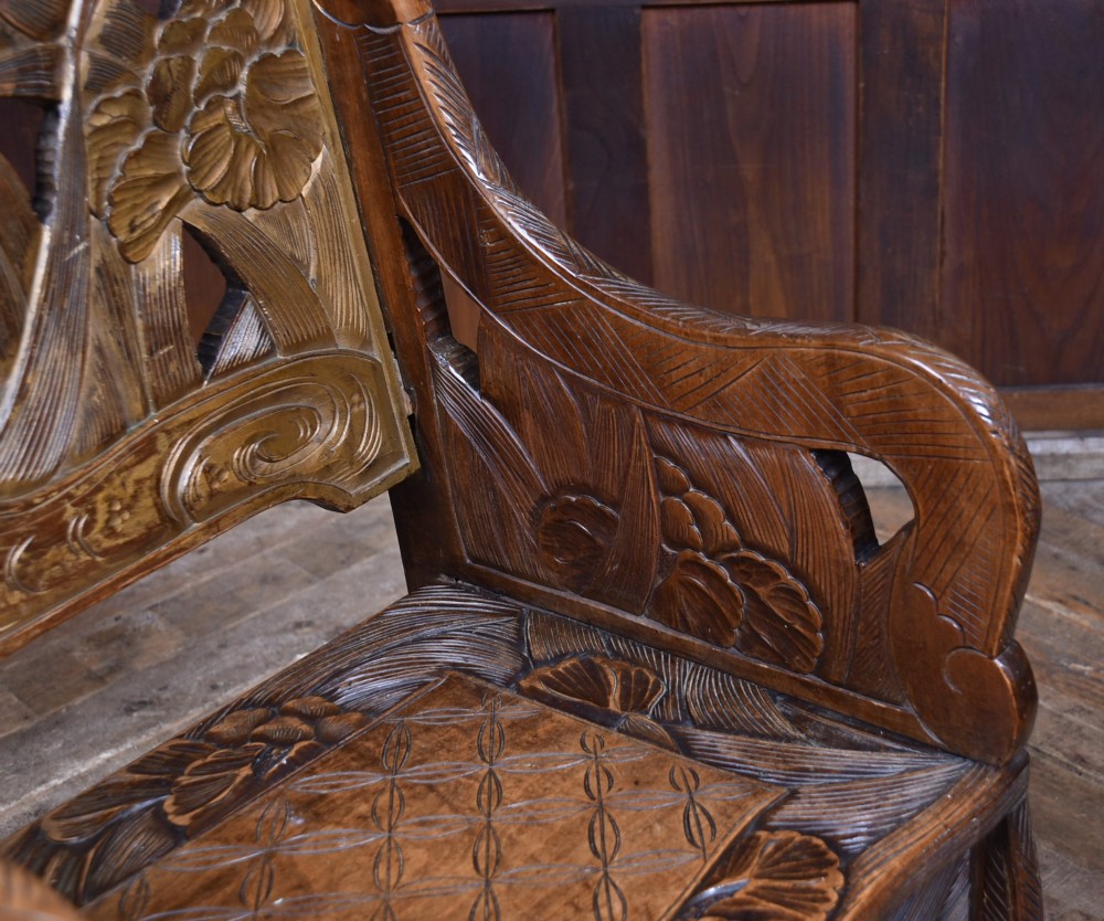 An antique carved walnut armchair featuring intricate floral relief carvings on the backrest, armrests, and legs. View VI
