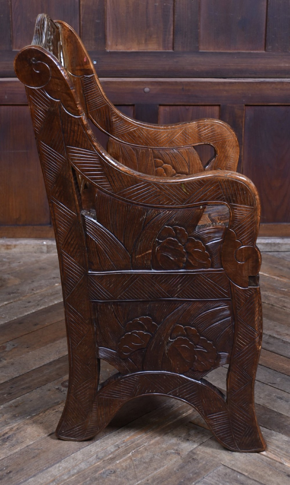 An antique carved walnut armchair featuring intricate floral relief carvings on the backrest, armrests, and legs. View VII