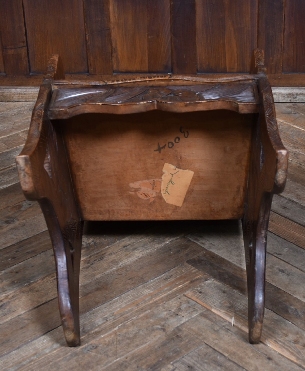 An antique carved walnut armchair featuring intricate floral relief carvings on the backrest, armrests, and legs. View X