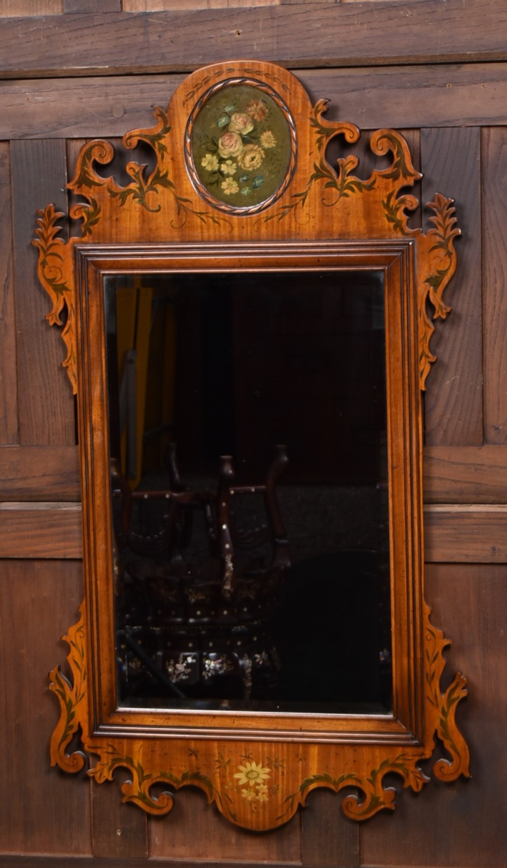 An Edwardian walnut wall mirror featuring a carved fretwork border, a painted floral oval crest, and marquetry leaf scroll details framing a central rectangular glass plate.
