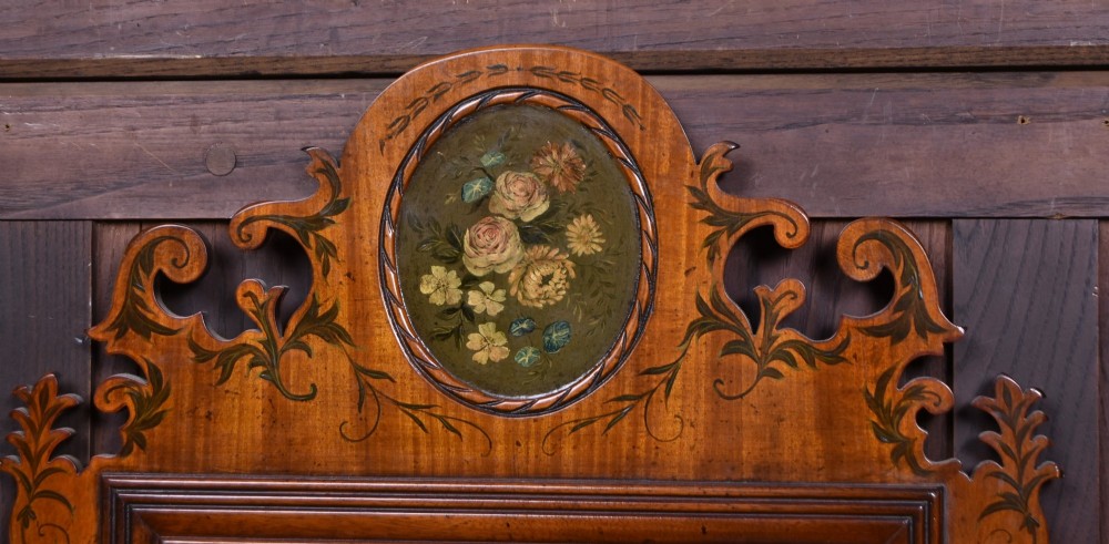 An Edwardian walnut wall mirror featuring a carved fretwork border, a painted floral oval crest, and marquetry leaf scroll details framing a central rectangular glass plate. View III