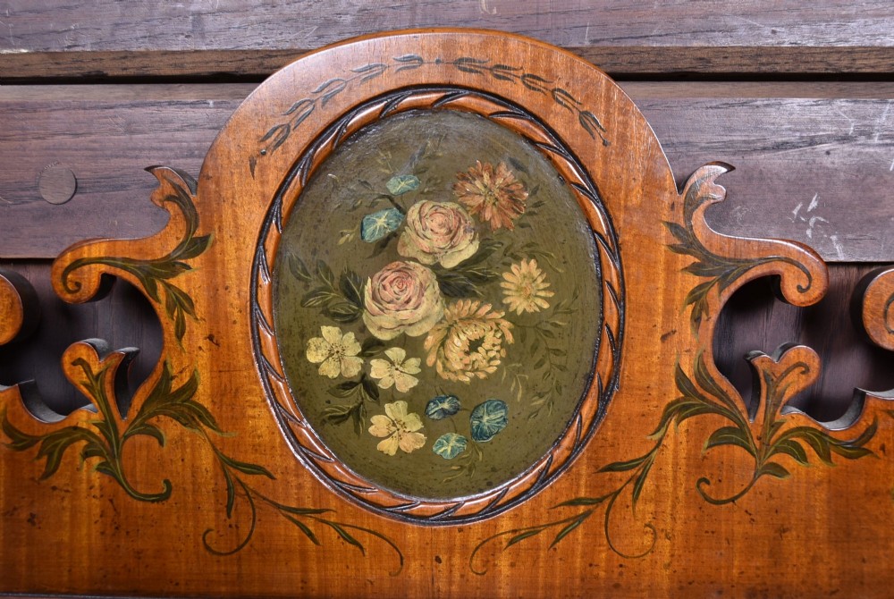 An Edwardian walnut wall mirror featuring a carved fretwork border, a painted floral oval crest, and marquetry leaf scroll details framing a central rectangular glass plate. View VI