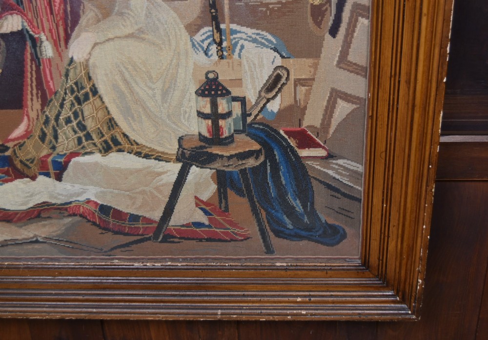 A framed needlepoint tapestry depicting figures and a crown inside an ecclesiastical interior with light streaming through a Gothic window. View III