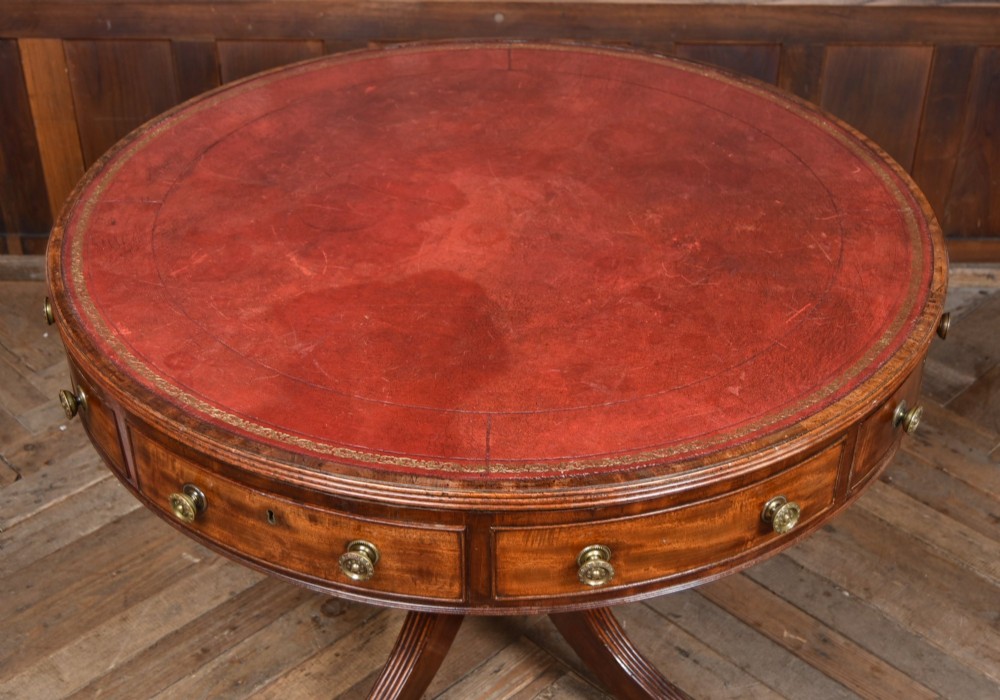 A circular Georgian mahogany drum table featuring a red leather inset top, frieze drawers with brass knobs, and a central pedestal with reeded splayed legs. View II