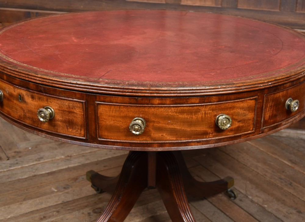 A circular Georgian mahogany drum table featuring a red leather inset top, frieze drawers with brass knobs, and a central pedestal with reeded splayed legs. View III