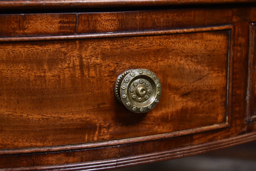 A circular Georgian mahogany drum table featuring a red leather inset top, frieze drawers with brass knobs, and a central pedestal with reeded splayed legs. View IV