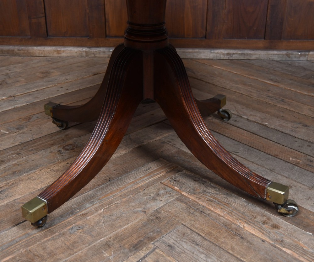A circular Georgian mahogany drum table featuring a red leather inset top, frieze drawers with brass knobs, and a central pedestal with reeded splayed legs. View V