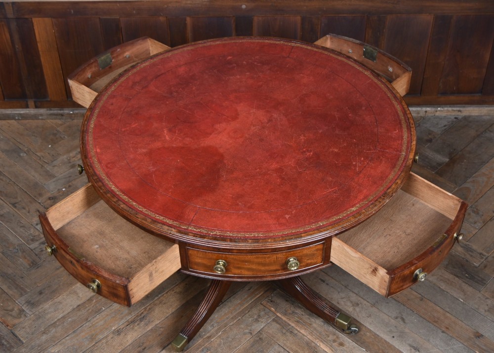 A circular Georgian mahogany drum table featuring a red leather inset top, frieze drawers with brass knobs, and a central pedestal with reeded splayed legs. View VII