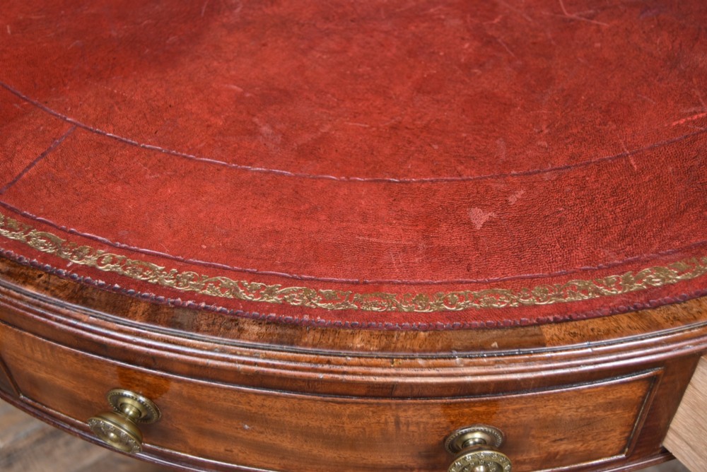 A circular Georgian mahogany drum table featuring a red leather inset top, frieze drawers with brass knobs, and a central pedestal with reeded splayed legs. View VIII