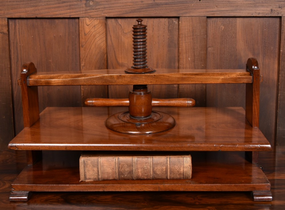A Victorian mahogany tabletop book press featuring a wooden central screw thread, turned crossbar handles, and a polished base.