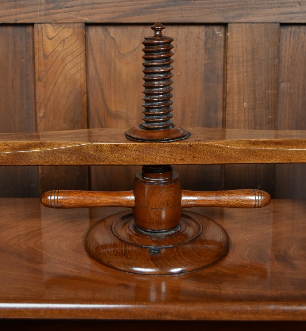 A Victorian mahogany tabletop book press featuring a wooden central screw thread, turned crossbar handles, and a polished base. View IV