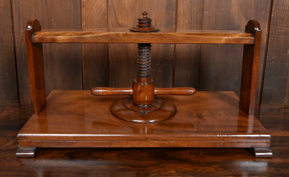 A Victorian mahogany tabletop book press featuring a wooden central screw thread, turned crossbar handles, and a polished base. View V