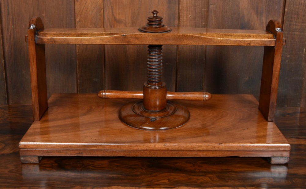 A Victorian mahogany tabletop book press featuring a wooden central screw thread, turned crossbar handles, and a polished base. View VI