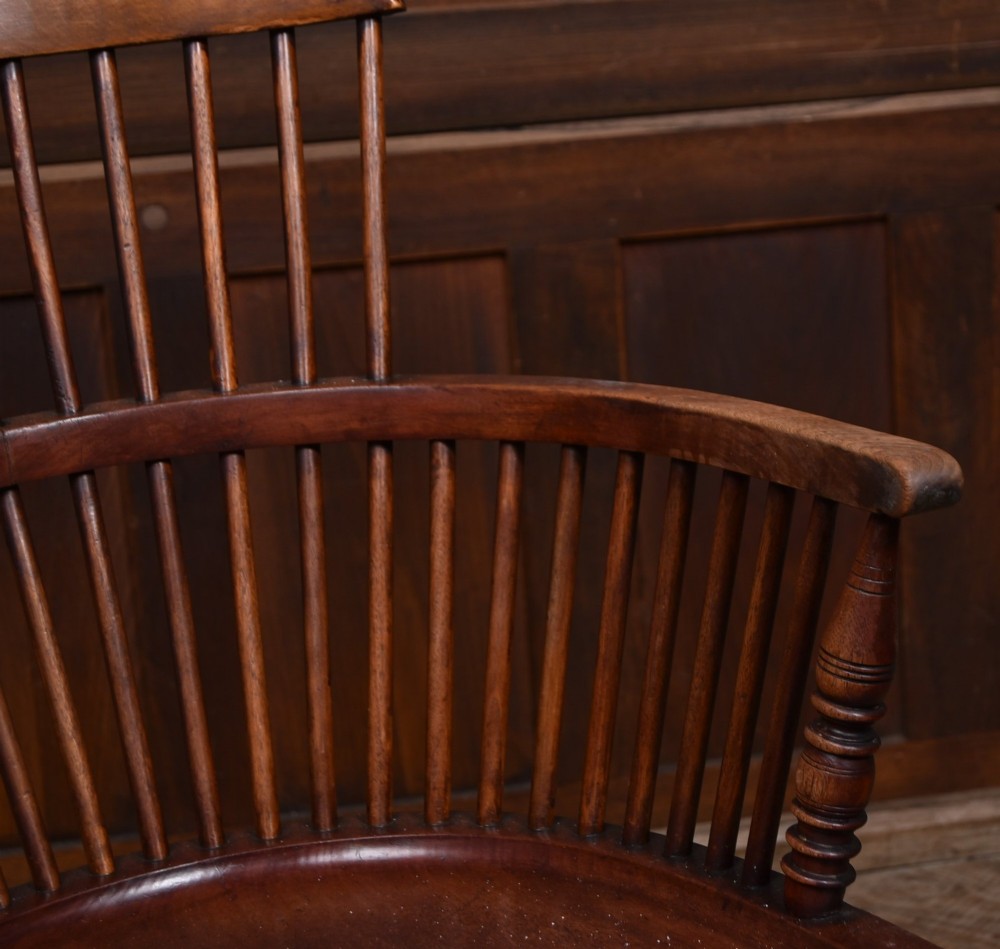 An Edwardian wooden comb-back Windsor armchair with turned legs, spindle backrest, and a contoured saddle seat. View II