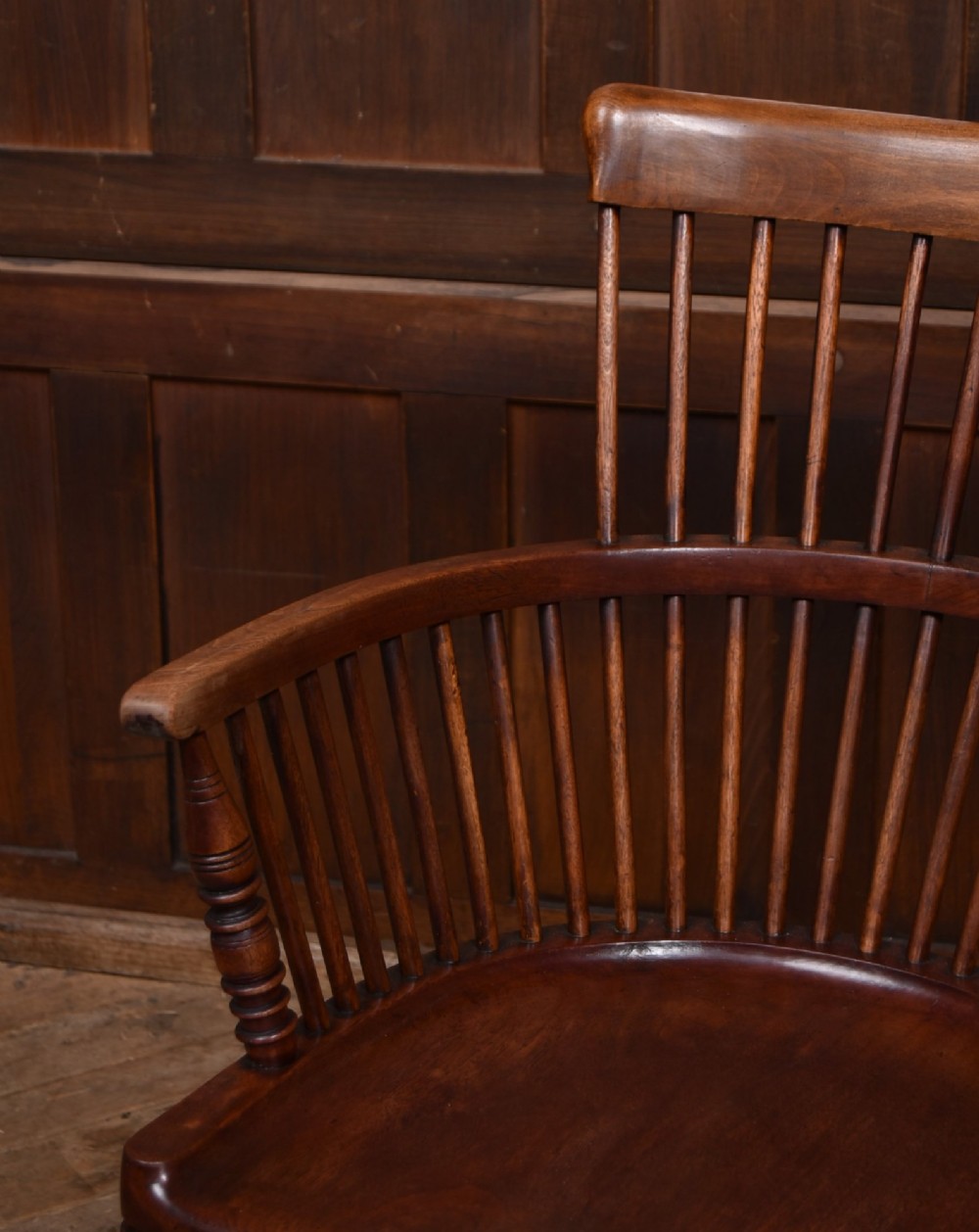 An Edwardian wooden comb-back Windsor armchair with turned legs, spindle backrest, and a contoured saddle seat. View III