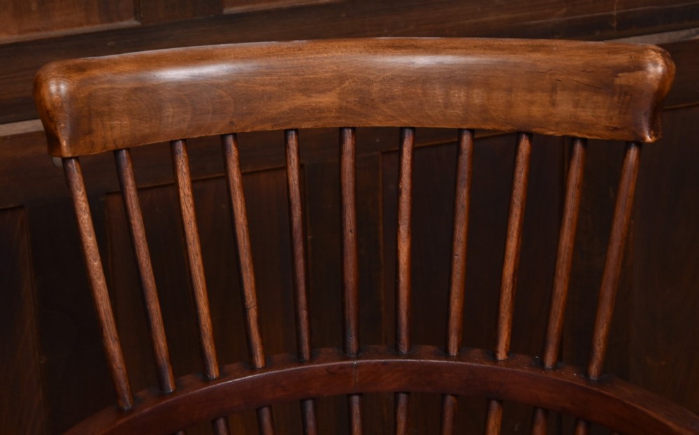 An Edwardian wooden comb-back Windsor armchair with turned legs, spindle backrest, and a contoured saddle seat. View IV