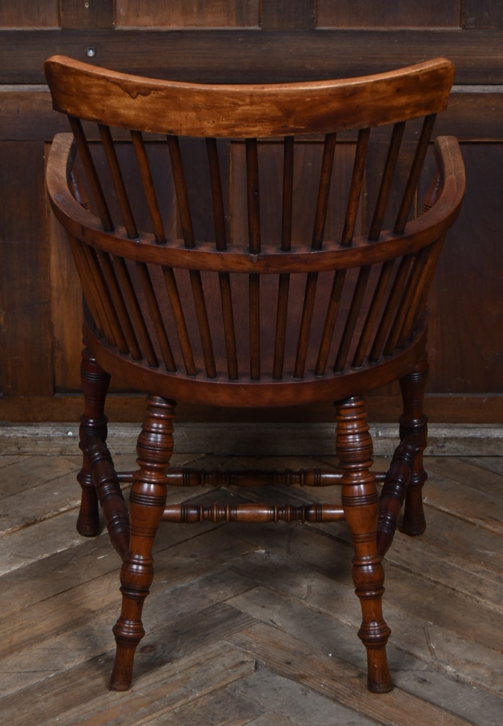 An Edwardian wooden comb-back Windsor armchair with turned legs, spindle backrest, and a contoured saddle seat. View VII