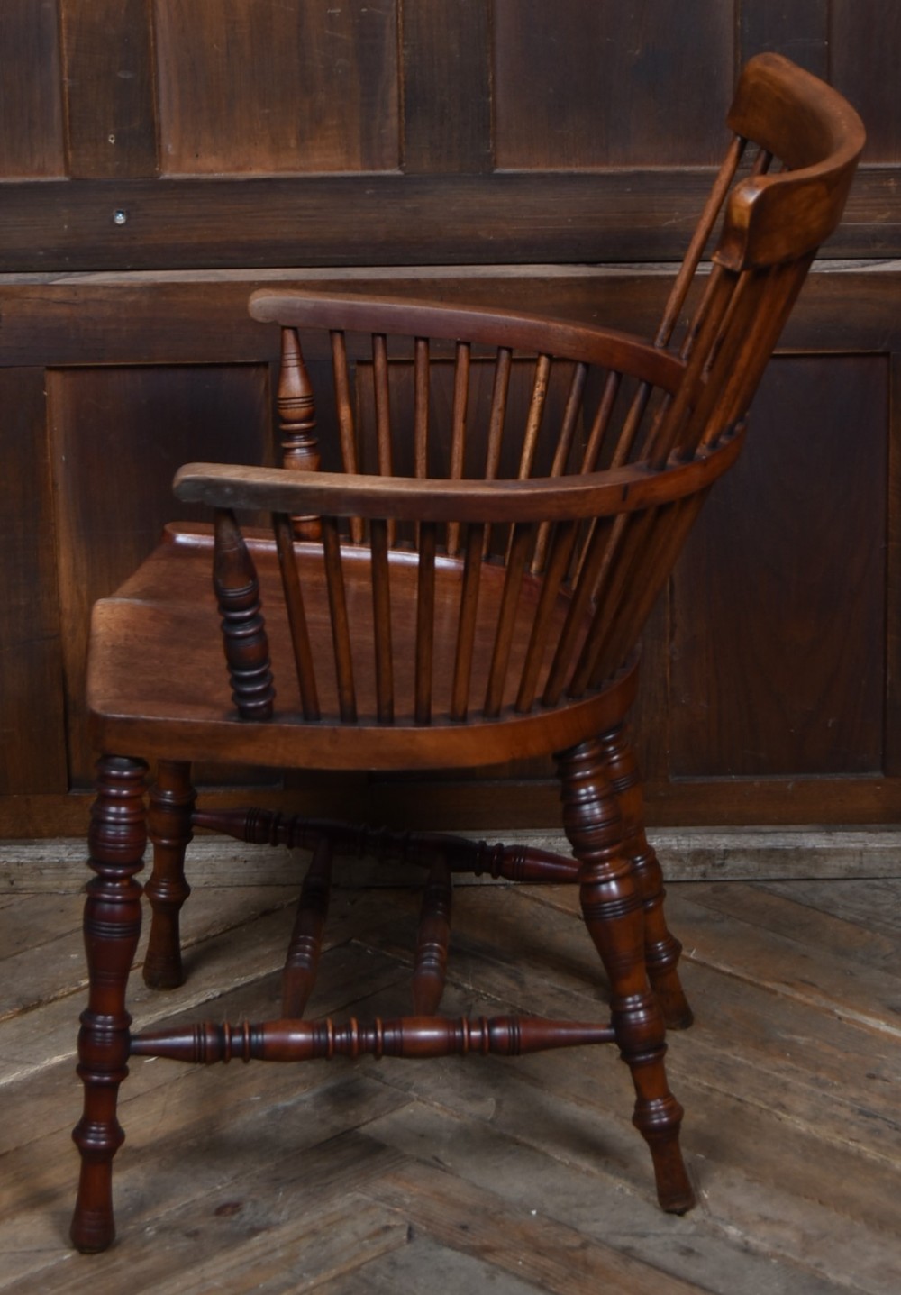 An Edwardian wooden comb-back Windsor armchair with turned legs, spindle backrest, and a contoured saddle seat. View VIII
