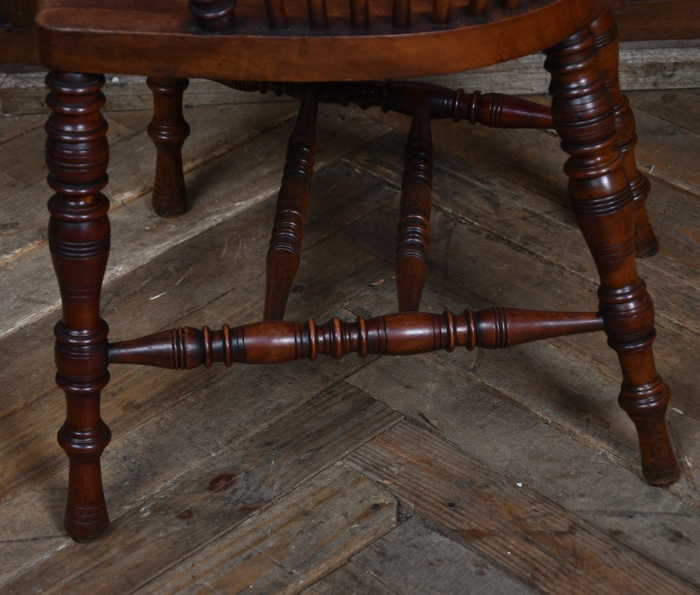 An Edwardian wooden comb-back Windsor armchair with turned legs, spindle backrest, and a contoured saddle seat. View IX