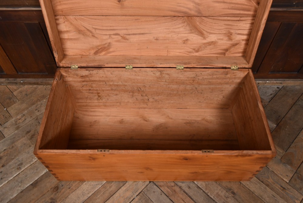 A rectangular warm amber camphor wood blanket box featuring exposed dovetail corner joints and metal side handles. View VII