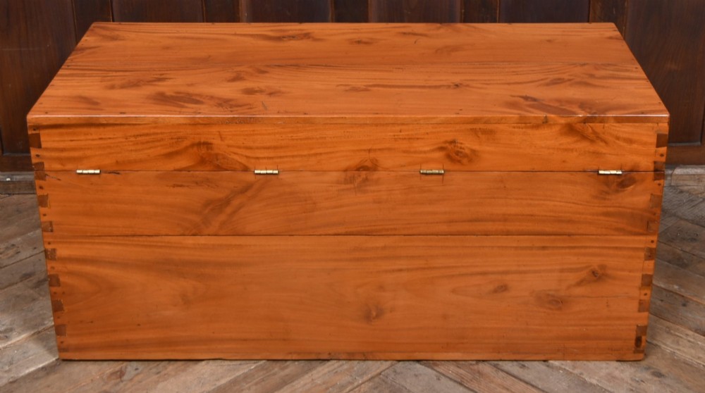 A rectangular warm amber camphor wood blanket box featuring exposed dovetail corner joints and metal side handles. View X