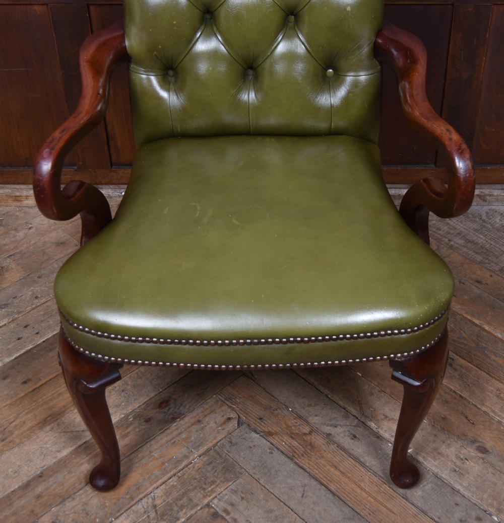 A high-backed desk chair featuring olive green button-tufted leather upholstery, carved dark wood armrests, brass stud trimming, and front cabriole legs. View V