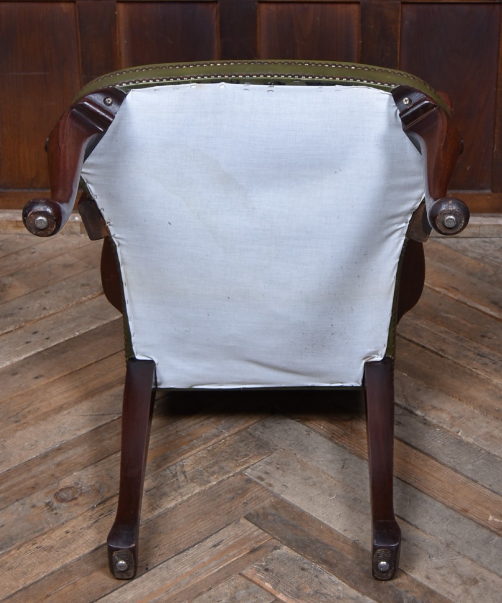 A high-backed desk chair featuring olive green button-tufted leather upholstery, carved dark wood armrests, brass stud trimming, and front cabriole legs. View XI