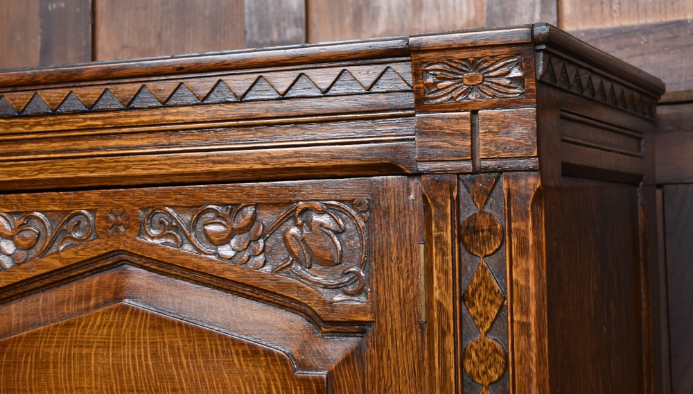 A narrow single-door Edwardian oak hall robe featuring geometric carved borders, a floral relief top panel, and rectangular lower door panels. View II